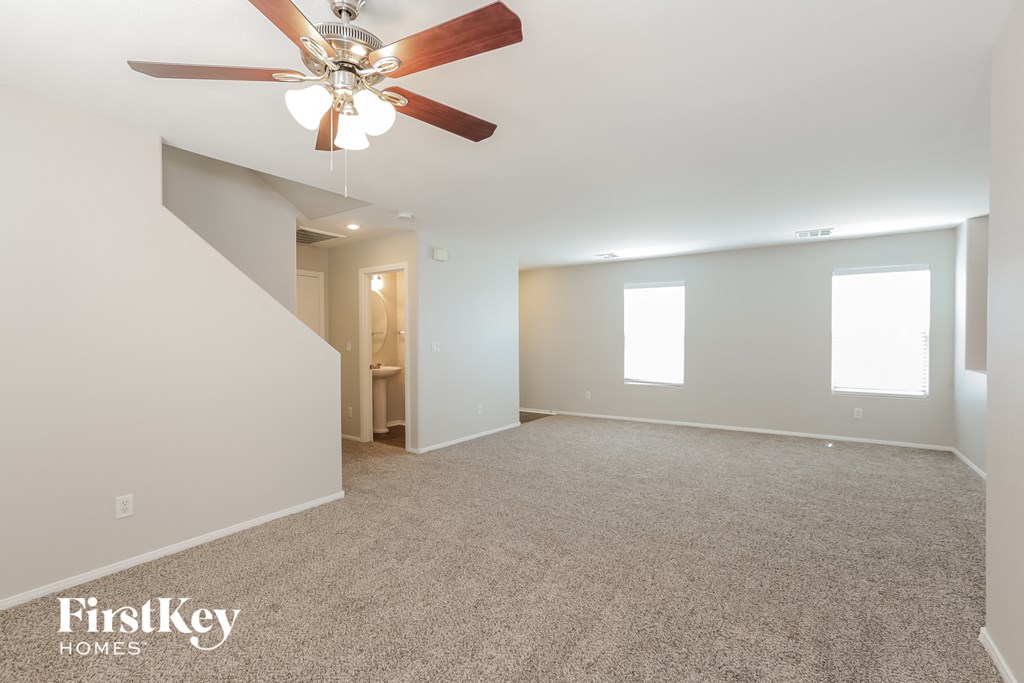 a spacious living room with carpet and a ceiling fan