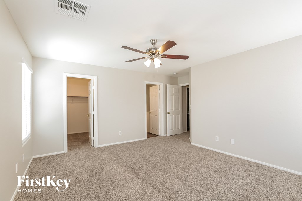 a spacious living room with carpet and a ceiling fan