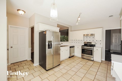A kitchen with a stainless steel refrigerator and white cabinets.
