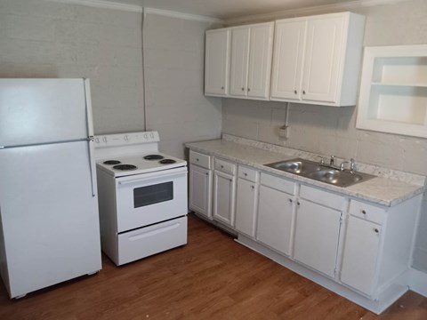 A white kitchen with a refrigerator, oven, and sink.