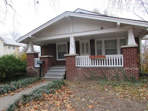 A house with a white porch and a brick base.