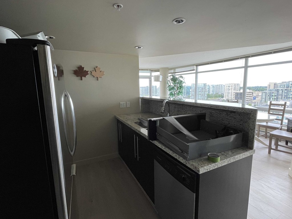 A kitchen with a black fridge and a black counter top.