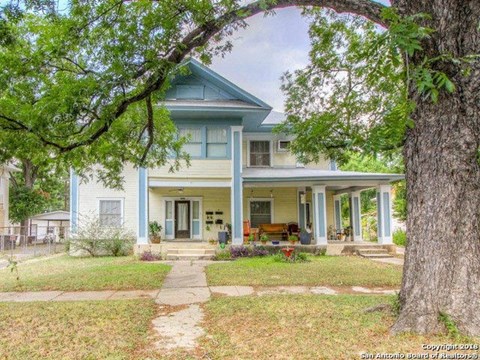 a blue house with a large tree in front of it