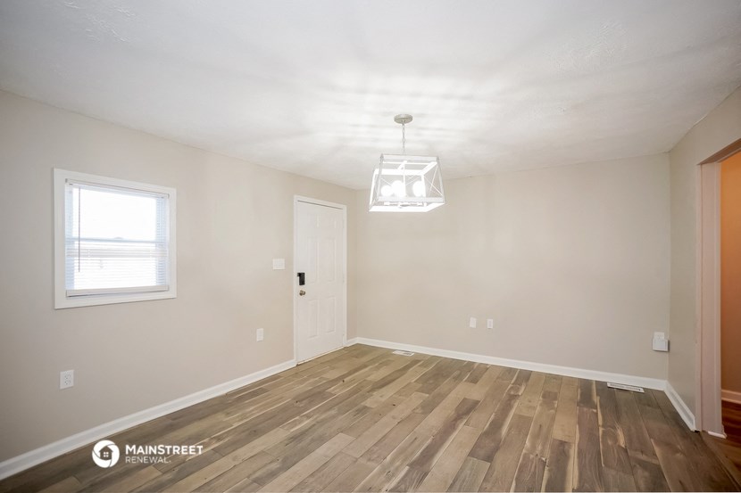 the spacious living room with hardwood flooring and a window