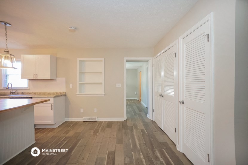 a spacious kitchen with white closet doors and a hallway to the living room