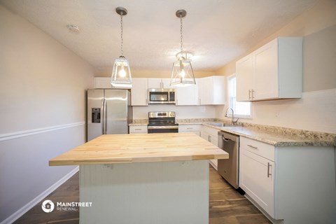 a kitchen with white cabinets and a wooden counter top