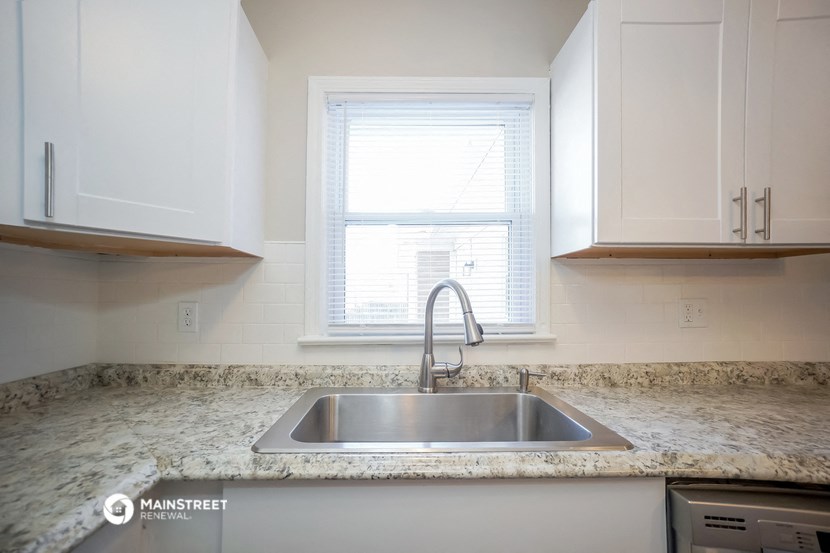 a kitchen with white cabinets and a sink and a window