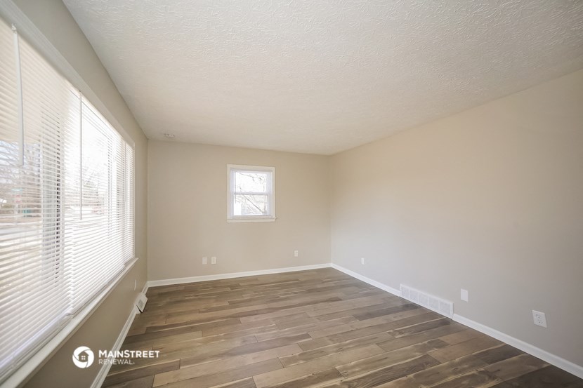 the spacious living room with wood flooring and large window