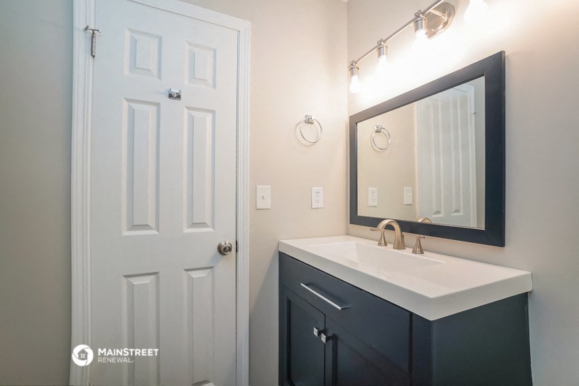 a bathroom with a sink and a mirror and a door