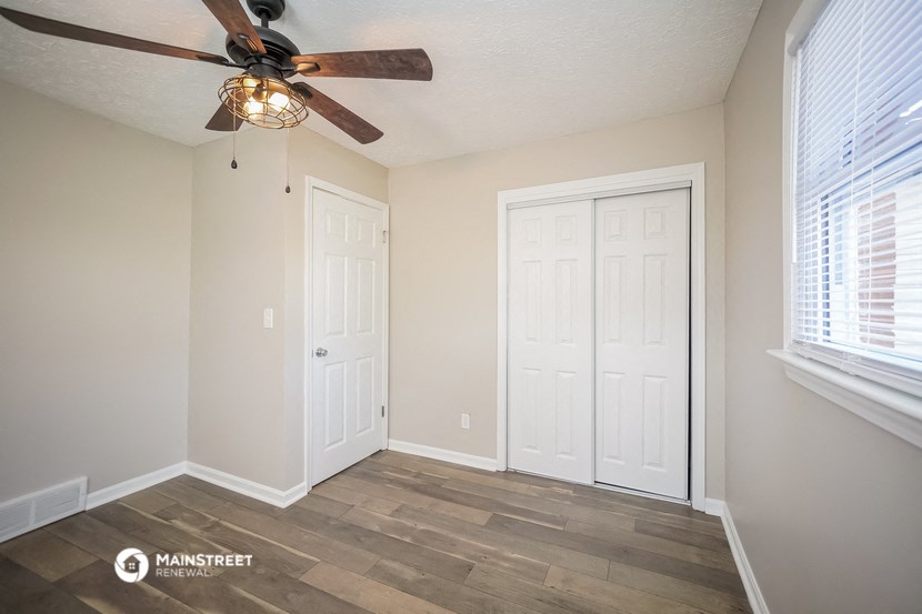 a bedroom with a ceiling fan and two closet doors
