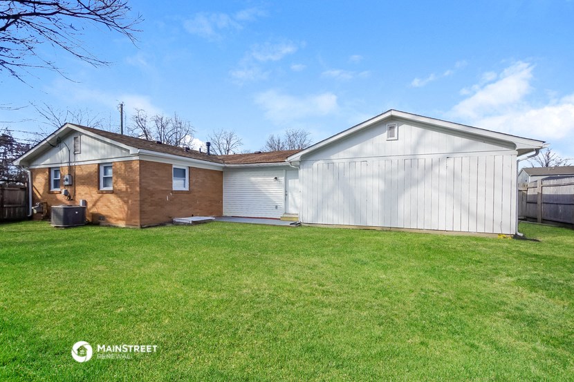 a home with a white garage and a brown house and a green lawn