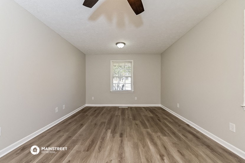 the spacious living room with hardwood flooring and a window