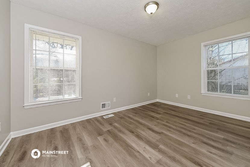 the living room of an empty home with wood flooring