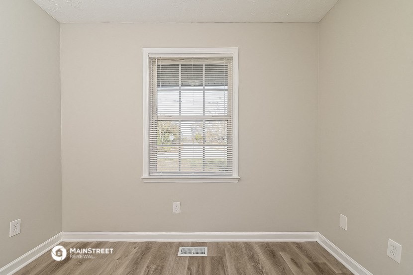 an empty room with a window and wooden floors