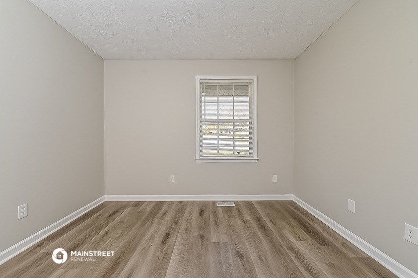 an empty room with wooden floors and a window