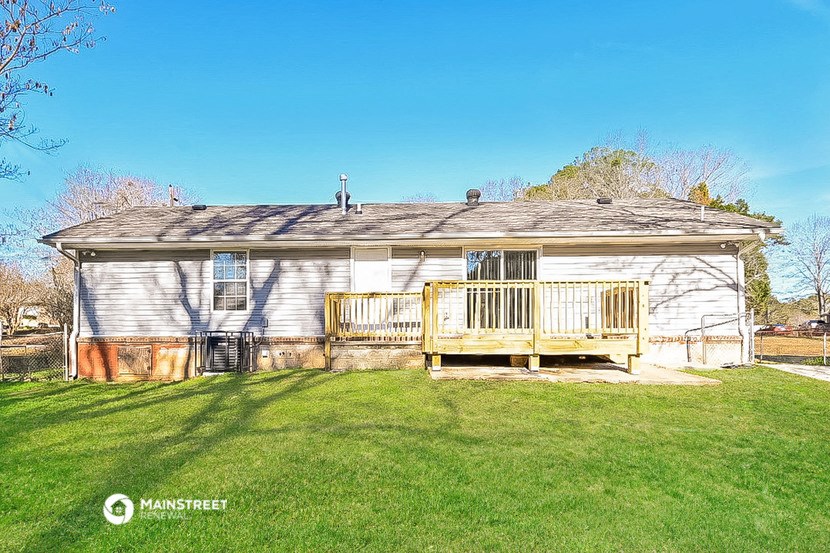 a small white house with a deck on the yard