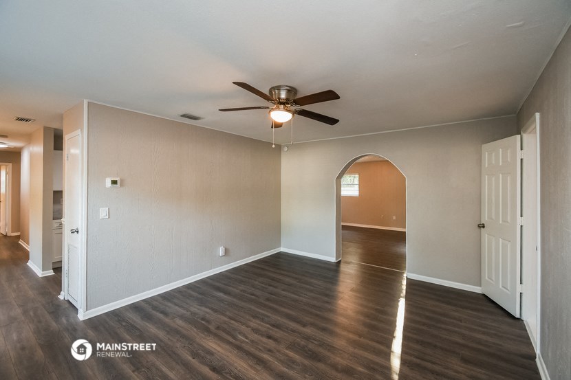 the living room and dining room of an empty house with a ceiling fan