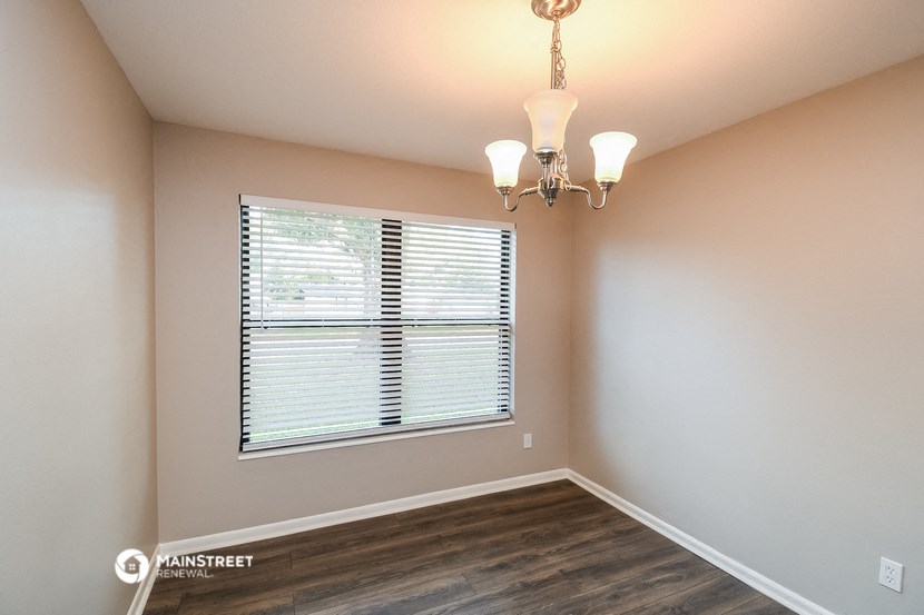 an empty bedroom with a large window and a chandelier
