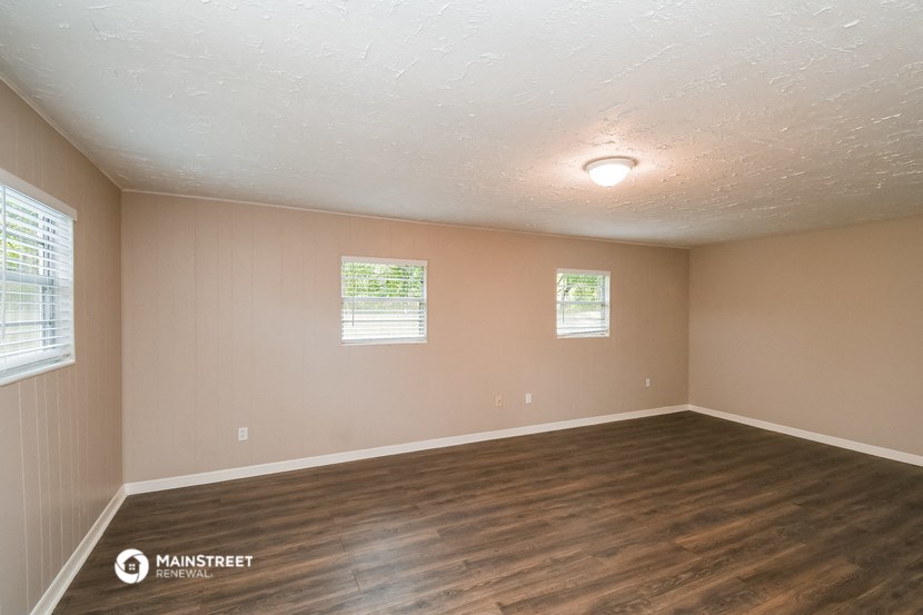 the spacious living room with wood flooring and windows