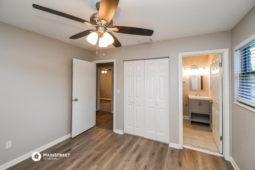 a living room with a ceiling fan and a door to a bathroom
