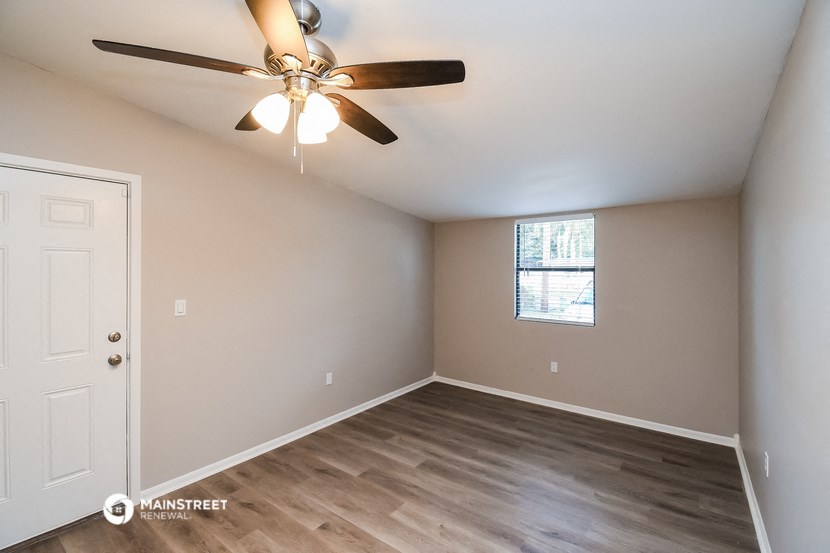 the spacious living room with ceiling fan and wood flooring