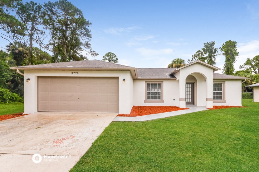 a beige house with a garage door and a lawn