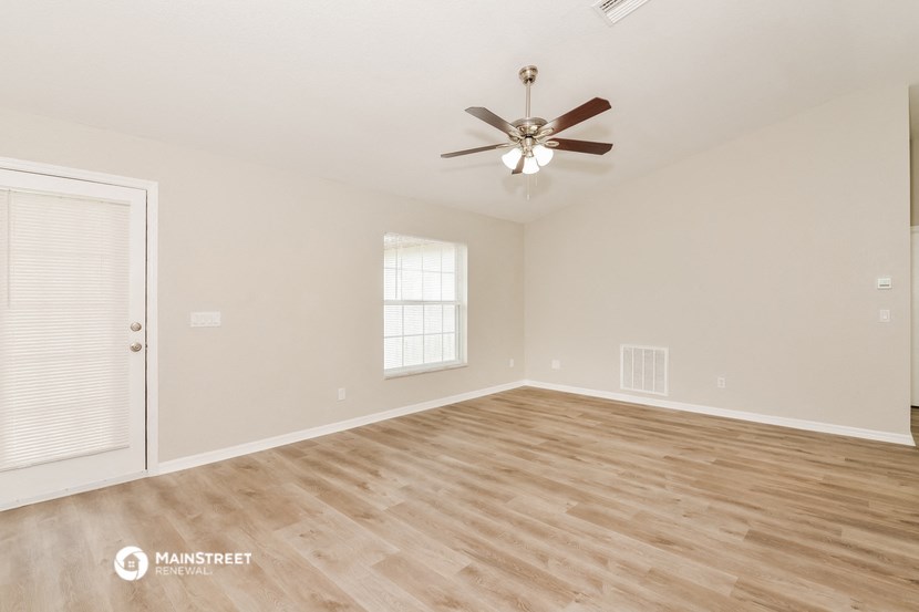 the spacious living room with hardwood floors and a ceiling fan