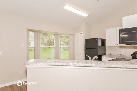 a kitchen with a counter top and a refrigerator and a window