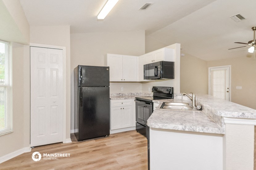 a kitchen with white cabinets and a black refrigerator