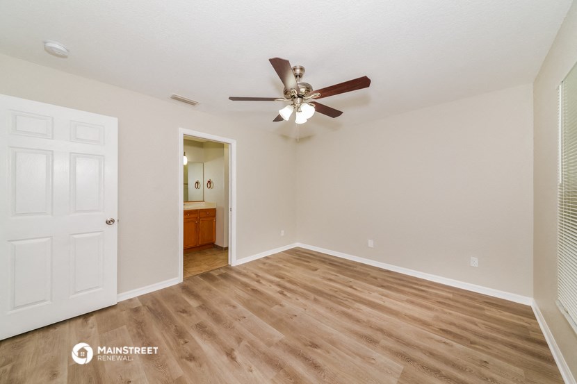 the spacious living room with ceiling fan and hardwood flooring