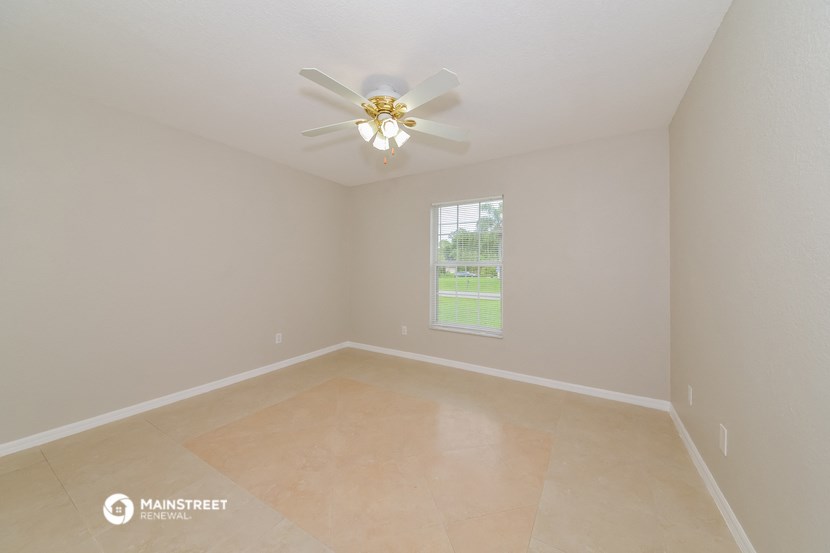 the spacious living room with ceiling fan and tiled floor