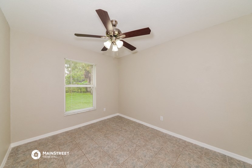 the spacious living room with ceiling fan and tile flooring