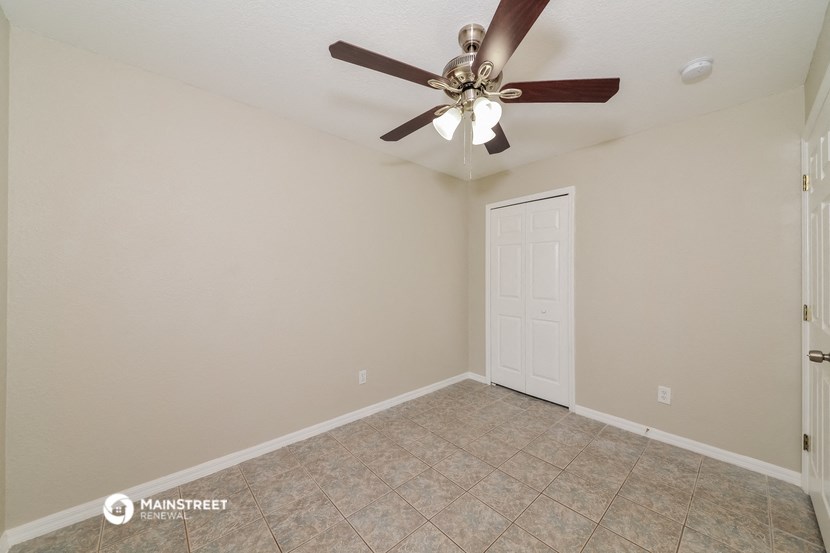 the spacious living room with ceiling fan and tile flooring
