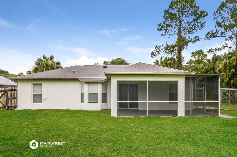 a white house with a grassy yard and a palm tree
