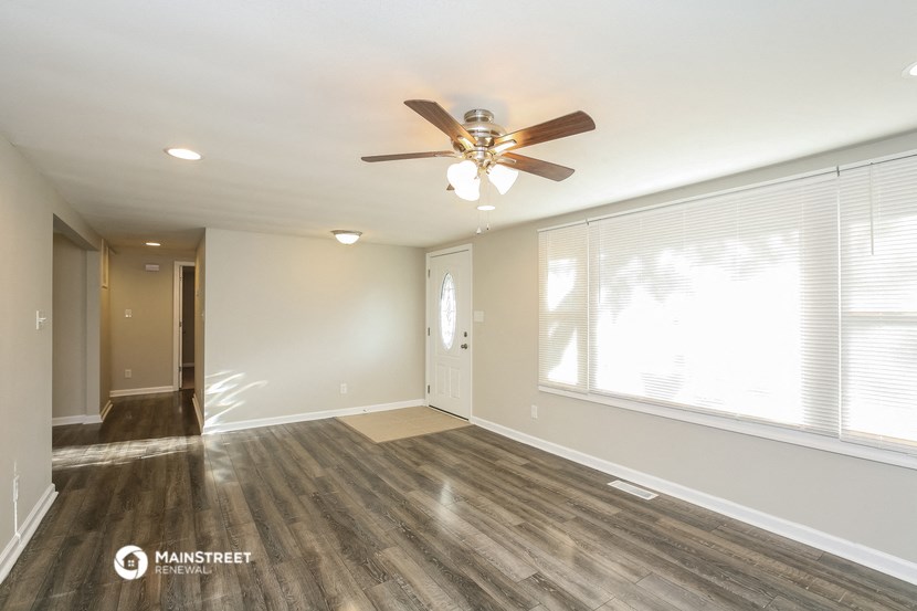 an empty living room with a ceiling fan and a large window