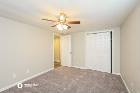 the spacious living room with carpet and a ceiling fan