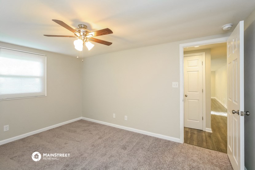 a bedroom with a ceiling fan and a door to a hallway