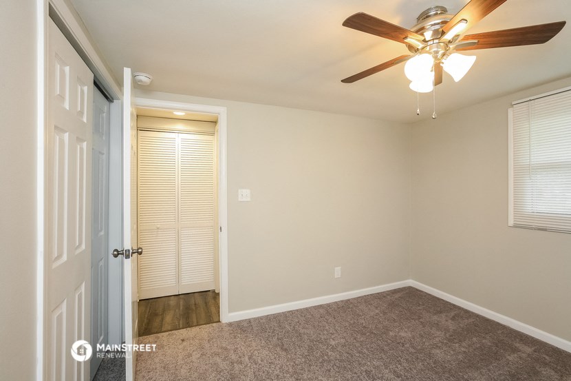 a bedroom with a ceiling fan and a door to a closet