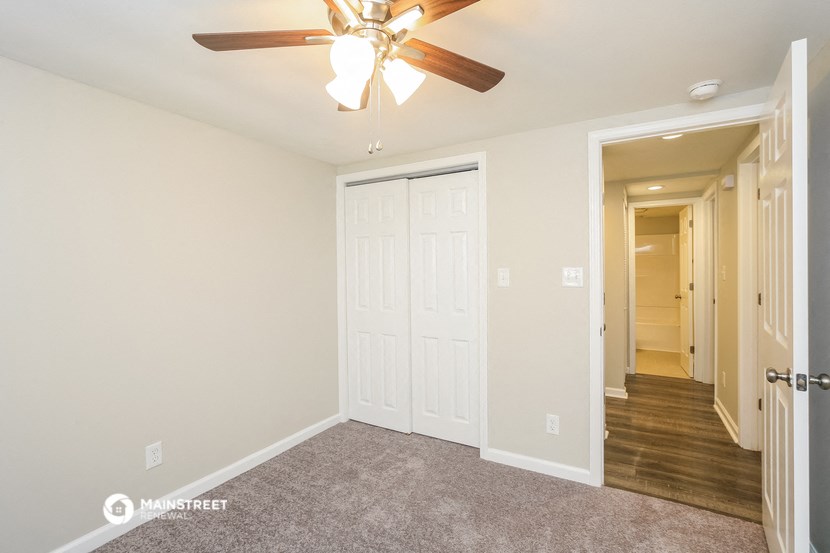 a bedroom with a ceiling fan and a hallway