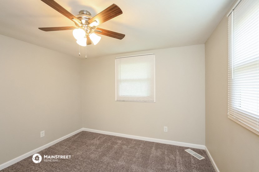 the upstairs bedroom has a ceiling fan and a large window