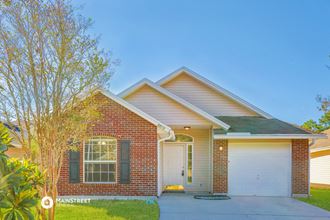 a brick house with a white garage door and a tree