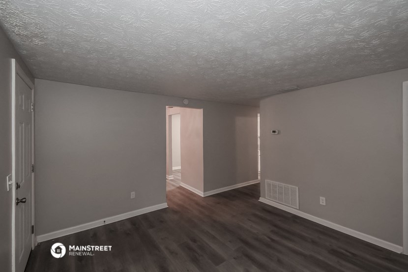 a living room with a hard wood floor and grey walls