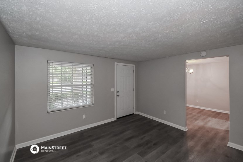 the living room of an empty house with a door and a window