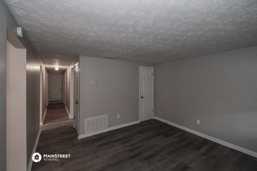 a living room and hallway with grey walls and wood floors