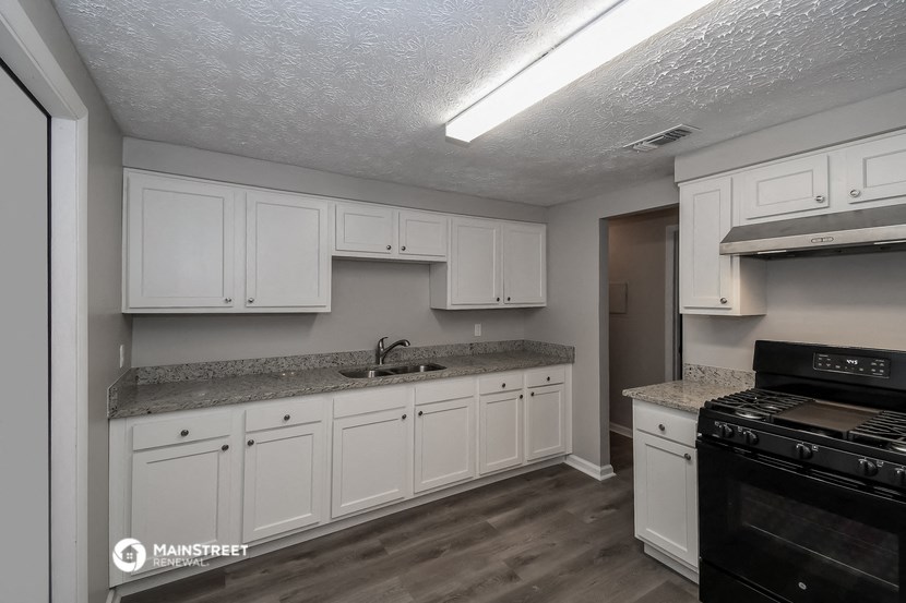 a kitchen with white cabinets and granite counter tops and black appliances
