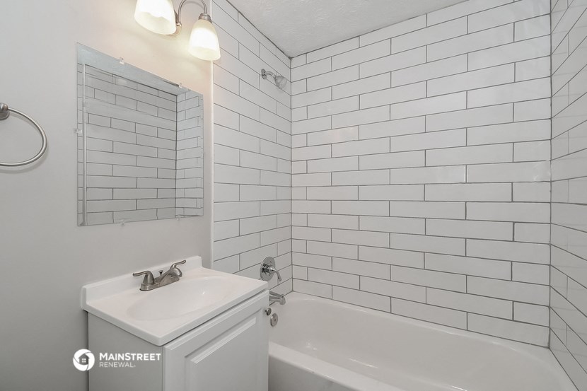 a white bathroom with white subway tiles and a white tub and sink