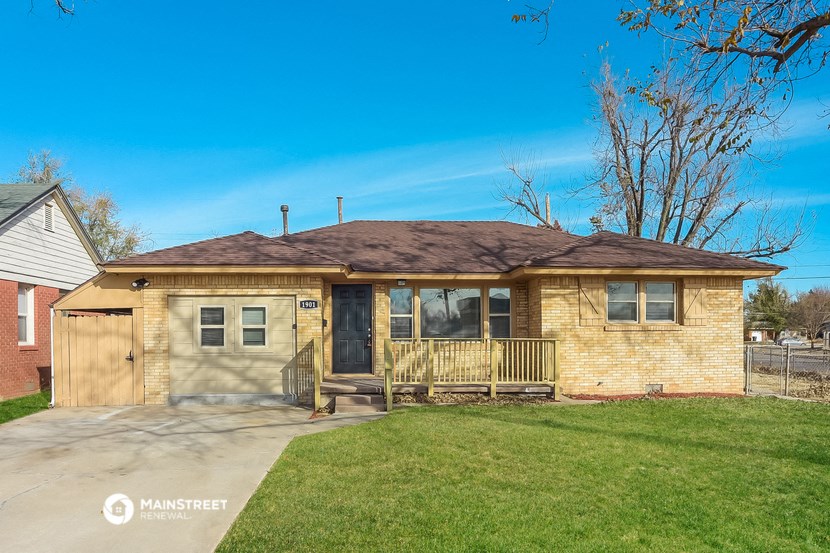 a small brick house with a porch and a lawn