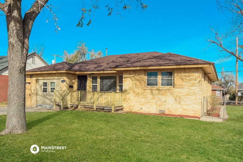 a yellow brick house with a yard and a tree