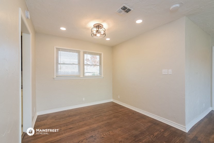 the spacious living room with hardwood flooring and a window