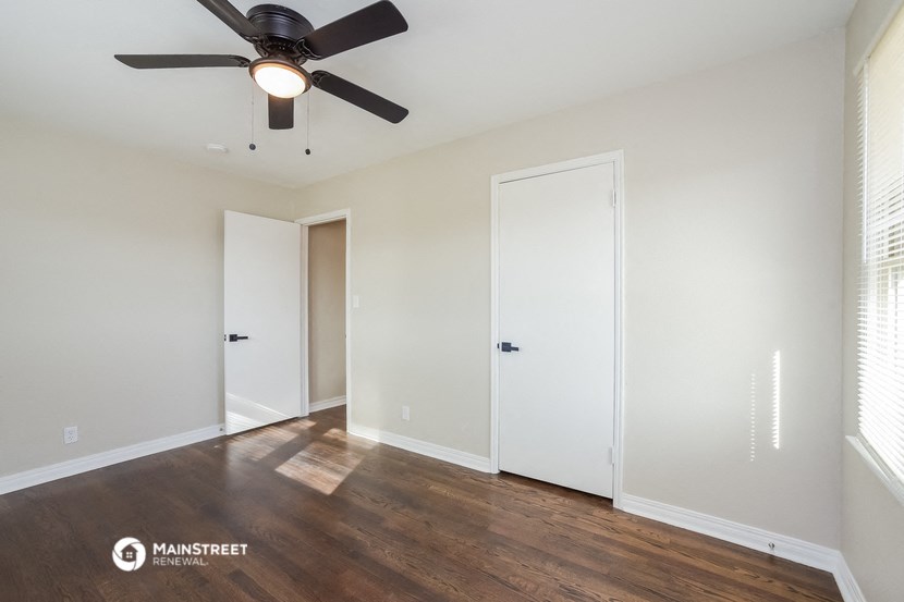 a living room with white walls and a ceiling fan